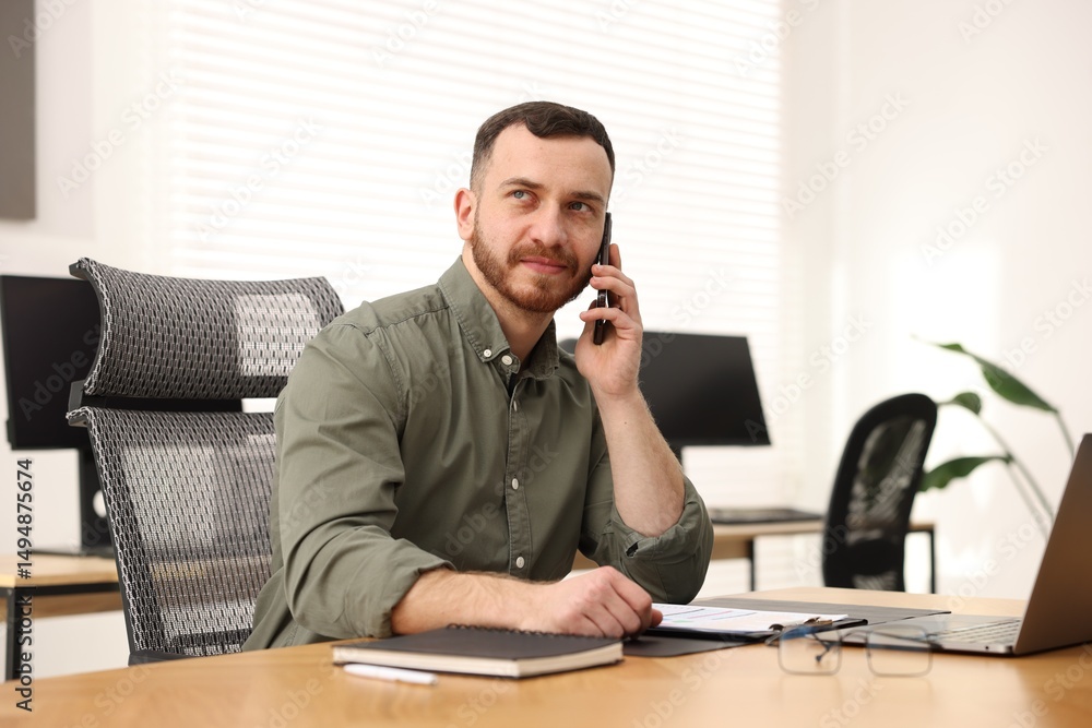 Poster man talking on phone while working at desk in office