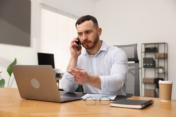 Man talking on phone while working at desk in office