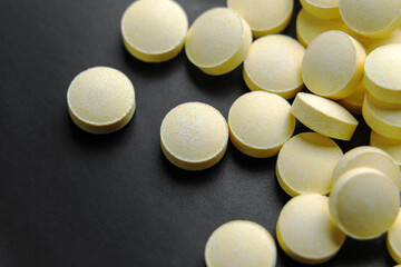 Pile of yellow painkiller pills on black ceramic surface. Macro shot.