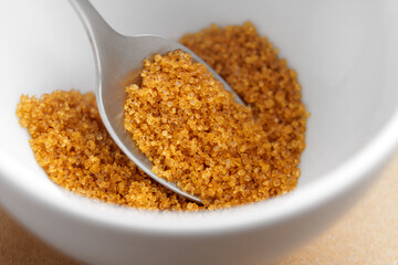 Portion of cane sugar in white tea cup with metal spoon. Top view. 