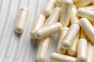 Beige pharmaceutical medicine capsules on white corrugated cardboard. Pack paper background. Macro shot