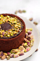 Dubai chocolate cheesecake with scattered pistachio nuts on ceramic plate close up