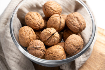 Full glass bowl with whole walnuts on fabric tablecloth. Close-up. Top view
