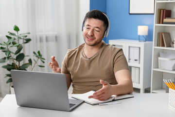 Man having online lesson with teacher via laptop at desk indoors