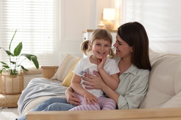 Happy mother and her cute daughter on sofa at home