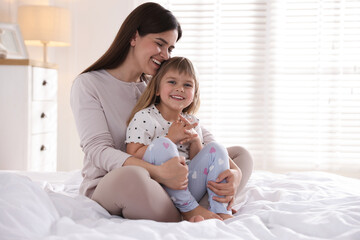 Mother and daughter on bed at home. Space for text