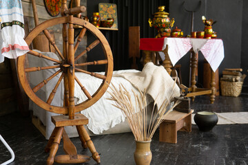 Old wooden spinning wheel and samovar in traditional russian house interior. Depicting folk craft,...