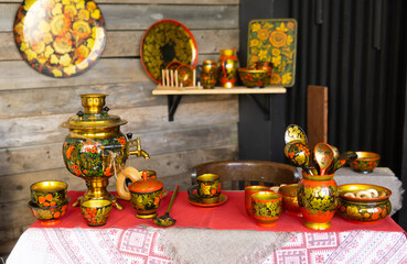 Golden samovar with vibrant khokhloma painting and traditional russian folk painted tableware on table scene depicting russian culture heritage hospitality and tea ceremony concept.