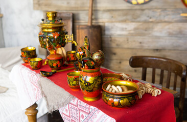 Traditional Khokhloma folk craft table setting with samovar, spoons, and snacks. Russian tea...
