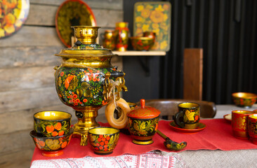 Samovar and traditional tea equipment with vivid Khokhloma painting on a table. Authentic russian...