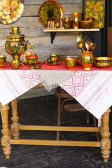 A table is set with traditional russian khokhloma painted teaware including a samovar, cups, and spoons. Russian folk art and culture concept for decoration.