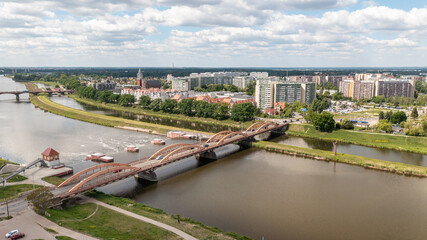 Naklejka premium Aerial panorama of arched traffic bridge over Odra River in Poland with surrounding buildings and urban landscape under cloudy sky