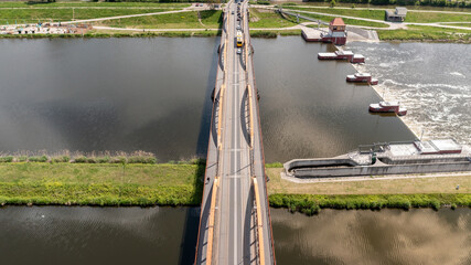 Aerial view of a bridge with vehicle traffic and nearby weir on river in Poland, infrastructure and...