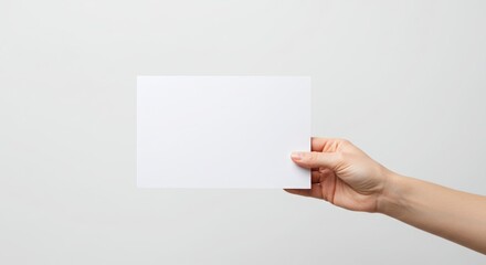 Obraz premium Hand holding a plain brochure or flyer with no branding or writing, photographed inside a professional photo studio on a pure white background 