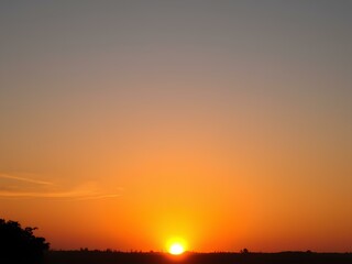 Naklejka premium Beautiful sunrise scene with the sun just above the horizon, casting warm orange and yellow hues across the sky and landscape