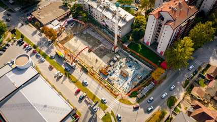Mixer trucks on the site, long pump for pouring concrete into building foundation,
