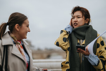 Two women engage in a conversation outdoors, one appears to be explaining something while gesturing...
