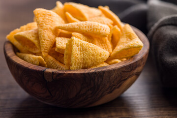 Salted snack chips in bowl on wooden table.