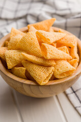 Salted snack chips in bowl on white table.