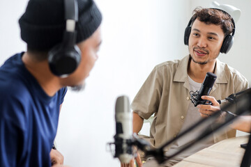 Two Men Having a Conversation While Co-hosting an Audio Broadcast in Home Studio
