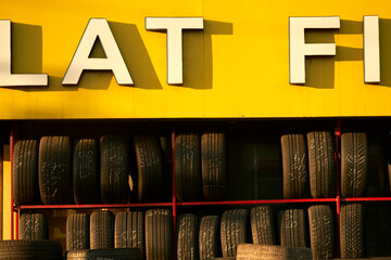 Tires stacked in a row under a bold yellow sign with large white letters. New York City, USA