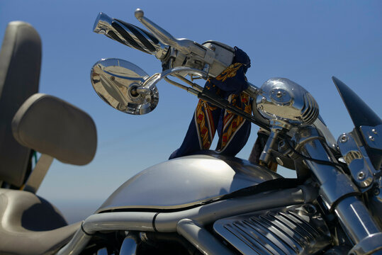Chrome motorcycle with ornate handlebars and a blue bandana under clear blue sky. Portugal