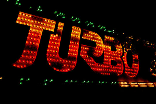 Brightly lit Turbo sign glowing with red and orange bulbs against a dark background. Austria