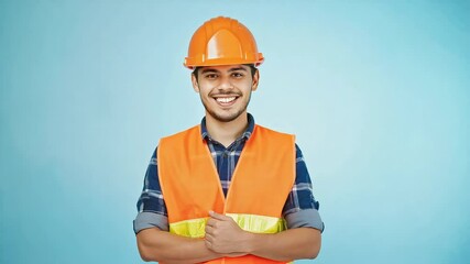 Smiling construction worker with arms crossed on blue background