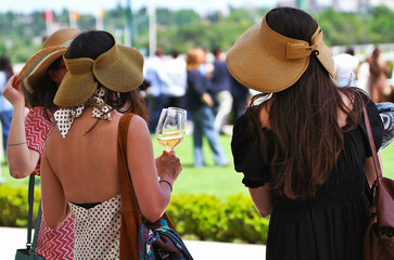 Verano con mujeres y amigas con clase elegantes tomando una copa de vino al aire libre con sombrero...