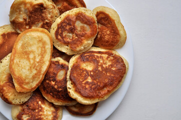 A close-up plate is filled with homemade pastries, pancakes with apples.