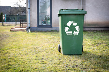 Green Recycling Bin Outdoors on Lawn Near Residential Building for Eco-Friendly Waste Management