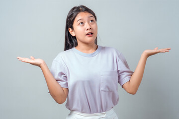 Young Asian woman in a light purple t-shirt stands against a plain background, looking up with...