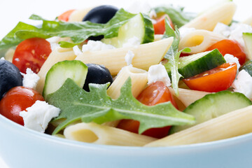 Mediterranean Pasta Salad in bowl with Fresh Vegetables and Herbs isolated on white background. Close up