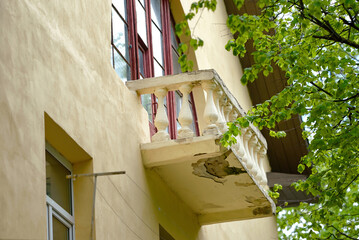 Architectural decay visible on historic balcony with damaged plaster, mildew patches, structural...