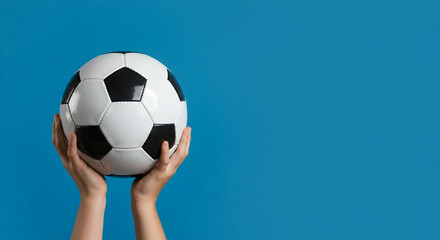 Naklejka premium Hands Holding Soccer Ball Against Bright Blue Background