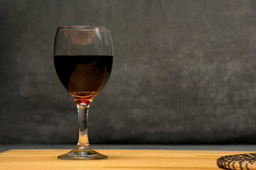 A glass of red (or white) wine placed on a table. A simple yet elegant composition evoking relaxation, fine dining, or a cozy evening atmosphere.

