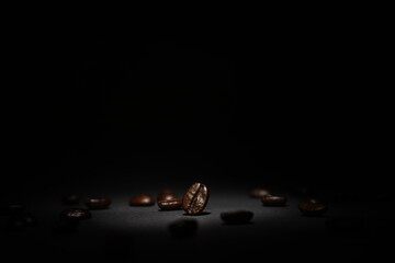 A central coffee bean stands out among others, illuminated by focused light that draws attention to its rich texture and deep roast color on a dark background.