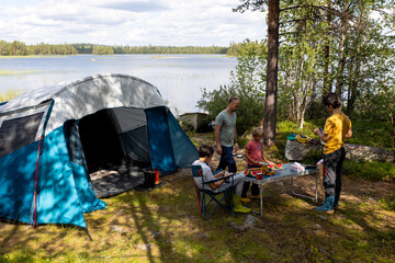 Happy children, eating breakfast and watermelon in the morning in front of a tent in a campsite in...