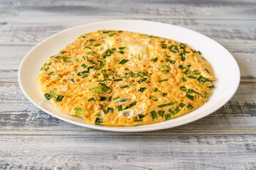 Fluffy omelet with fresh chives on a white plate. Delicious egg dish for breakfast, brunch, or...
