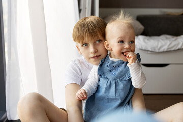 Portrait children together at home. Beautiful girl and boy, brother and sister hugging inside...