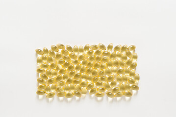 Many transparent orange colored oval shaped capsules scattered on a white background, omega 3 fish oil, lecithin, vitamin D. Border with copy space, mockup
