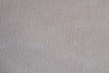 Beige textile fabric with visible woven texture. Close-up macro photograph of neutral canvas material. Natural fiber texture. Design for textile, wallpaper, print, background. Macro shot