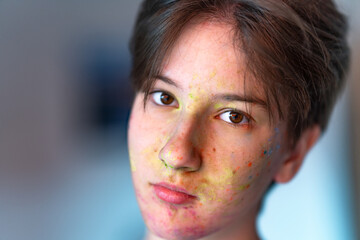Artistic soft focus portrait of a young face with multicolored paint splashes. Expressive modern...