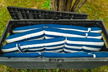 Cozy striped cushions stored neatly in a garden chest underneath a tree