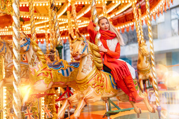Woman enjoys festive atmosphere on carousel ride at winter fair with vibrant lights and colorful decorations in the background