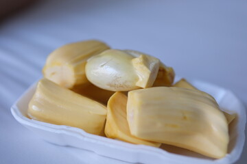 Close-up view of ripe yellow jack fruit pieces arranged in transparent trays, showcasing their vibrant color and freshness, ready for sale or serving as a tropical treat. Delicious Freshly Pack.