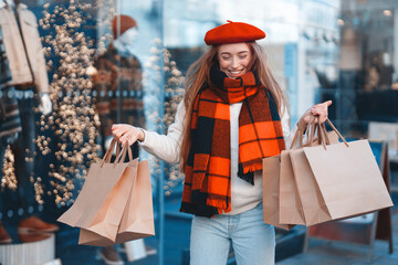 Woman shopping and enjoying the festive atmosphere while holding multiple bags outside a boutique during the winter season