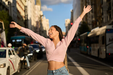 Young latin woman celebrating with open arms in a city street