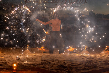 Fire performer lights up the beach, creating beautiful patterns against a sunset backdrop. 