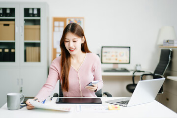 Young female graphic designer using digital tablet and laptop in modern office. Creative workspace,...